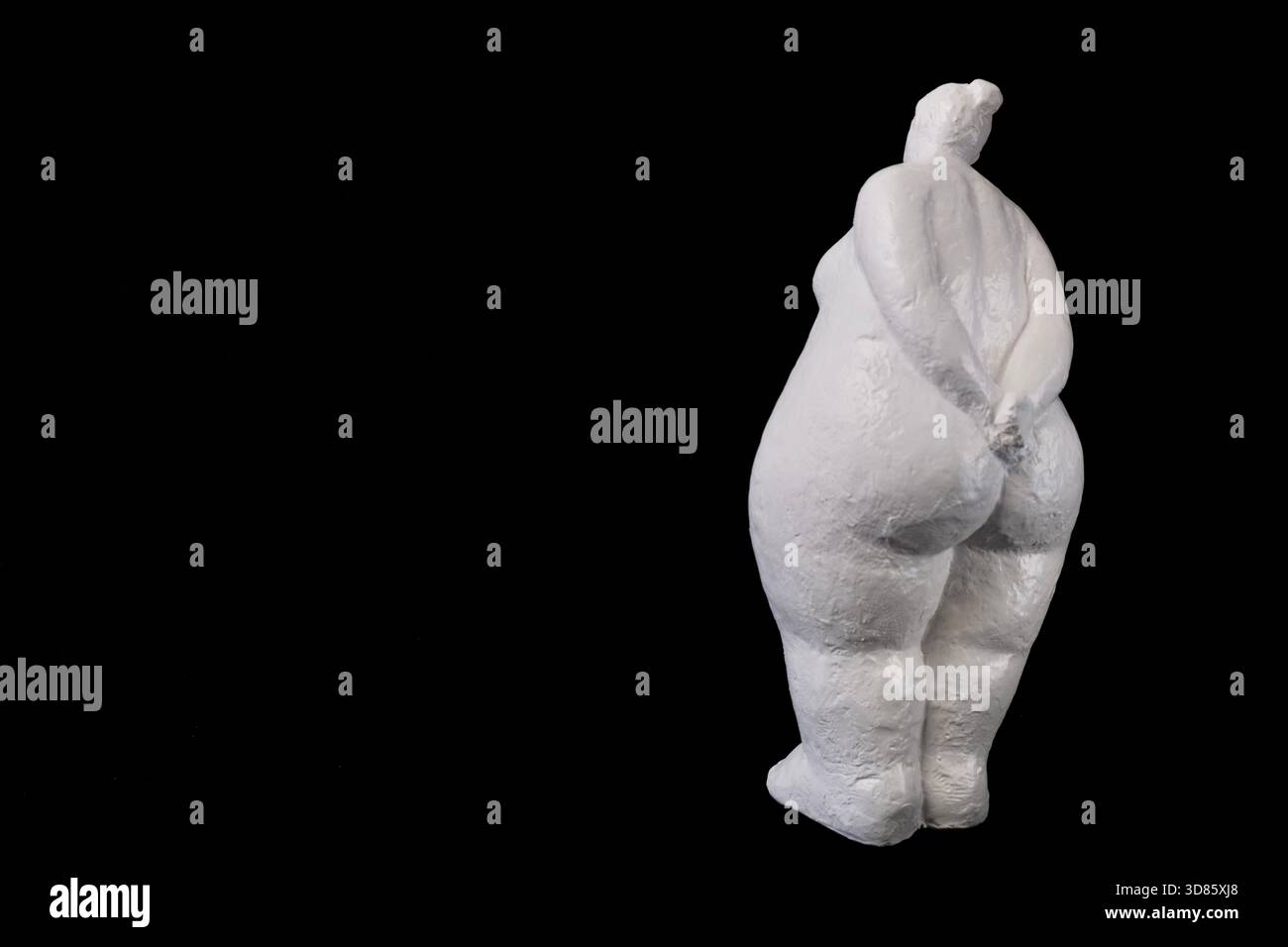 Weiße Gipsfrau-Statue auf schwarzem Hintergrund. Rückansicht. Stockfoto