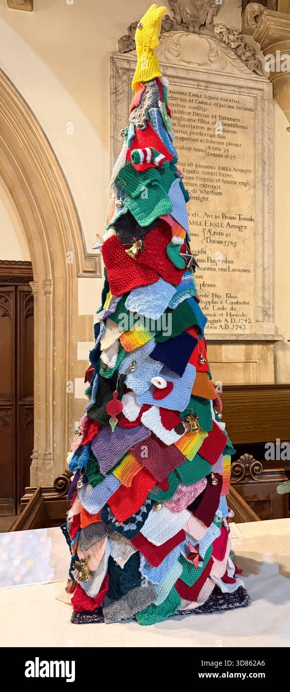 Farbenfroher handgefertigter Weihnachtsbaum aus gestrickten Stoffquadraten und Dekorationen, die im Weihnachtsbaumfest der St. Mary's Church Calne ausgestellt sind Stockfoto