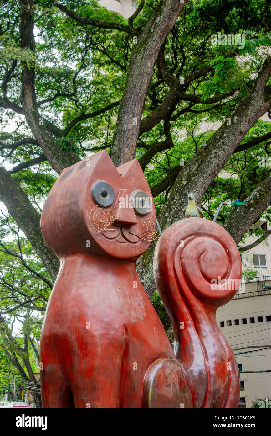 Cat Park, Cali, Valle del Cauca, Kolumbien - 9. November 2025 - Eine skurrile Katzenskulptur, umgeben von üppigem Grün, mit einem Vogel in der Nähe. Stockfoto