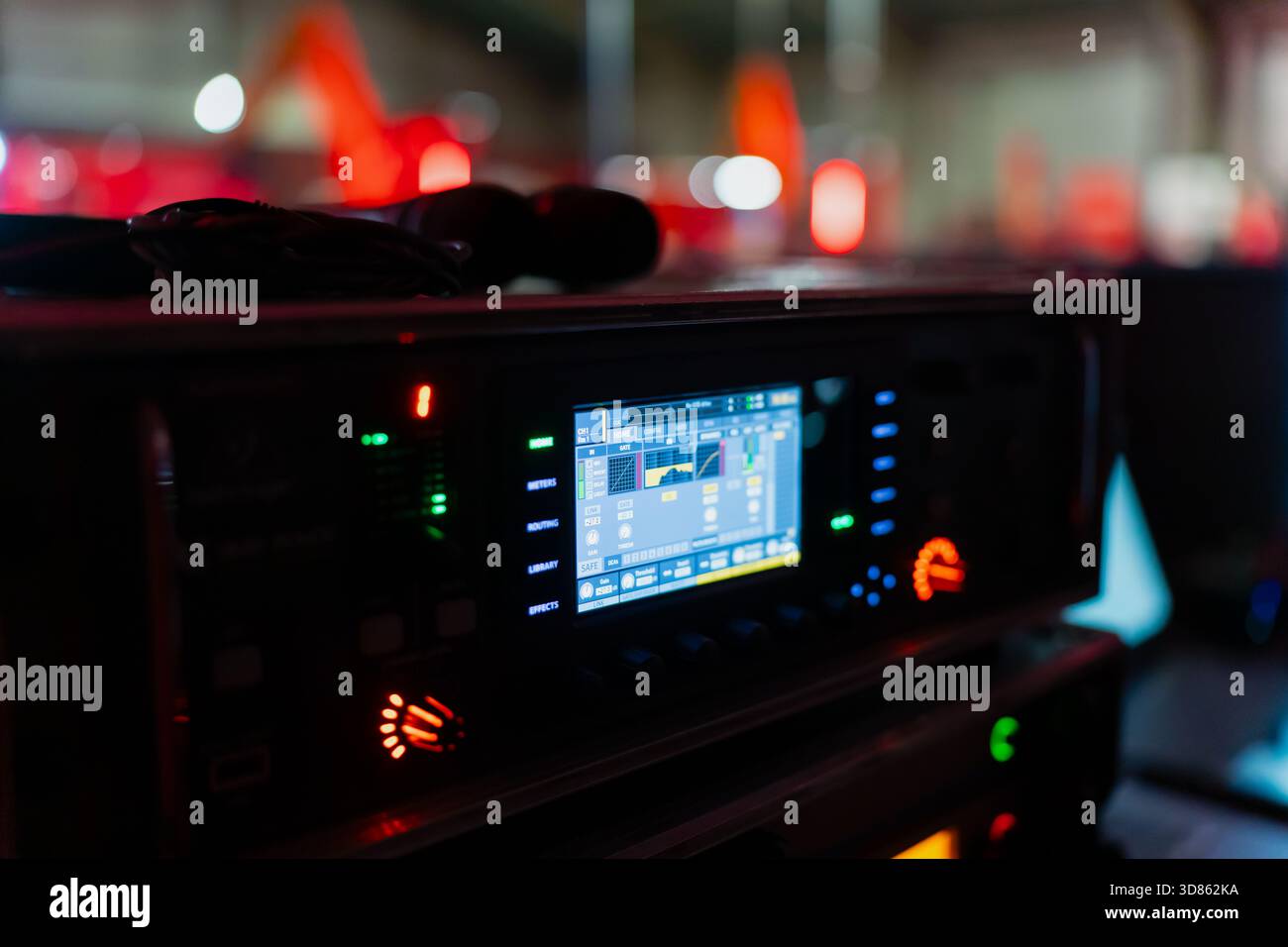 Nahaufnahme der Produktionsanlagen auf der Bühne mit beleuchtetem digitalem Display mit Messgeräten und Bedienelementen in dunkler Backstage-Umgebung mit verschwommenem Rot l Stockfoto