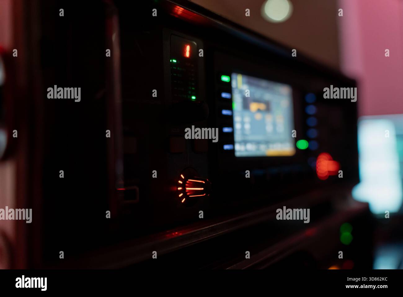 Nahaufnahme der beleuchteten Tischsteuerungsgeräte mit Leuchtknöpfen, Signalanzeigen und unscharfer digitaler Anzeige bei schwachem Licht hinter der Bühne e Stockfoto