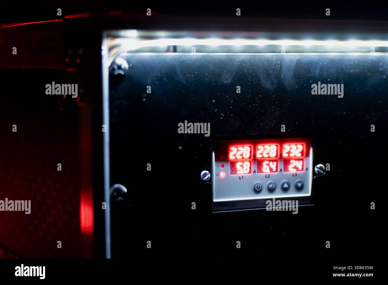 Industrielle Gerätetafel mit beleuchteten roten numerischen Werten auf einem kompakten digitalen Bildschirm, umrahmt von Metallteilen und verstärkt durch eine helle Ove Stockfoto
