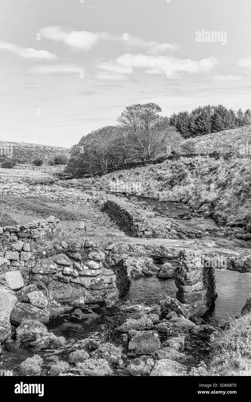 Historische mittelalterliche Clapper Bridge im Dartmoor-Nationalpark, Devon, England in Schwarz-weiß Stockfoto