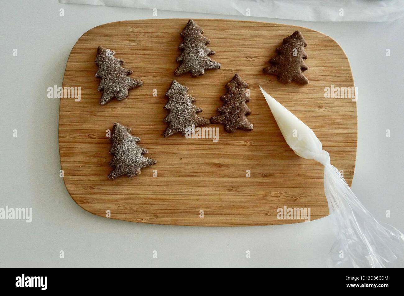 Kekse in Form eines Weihnachtsbaums auf einem Holzbrett mit weißem Hintergrund Stockfoto