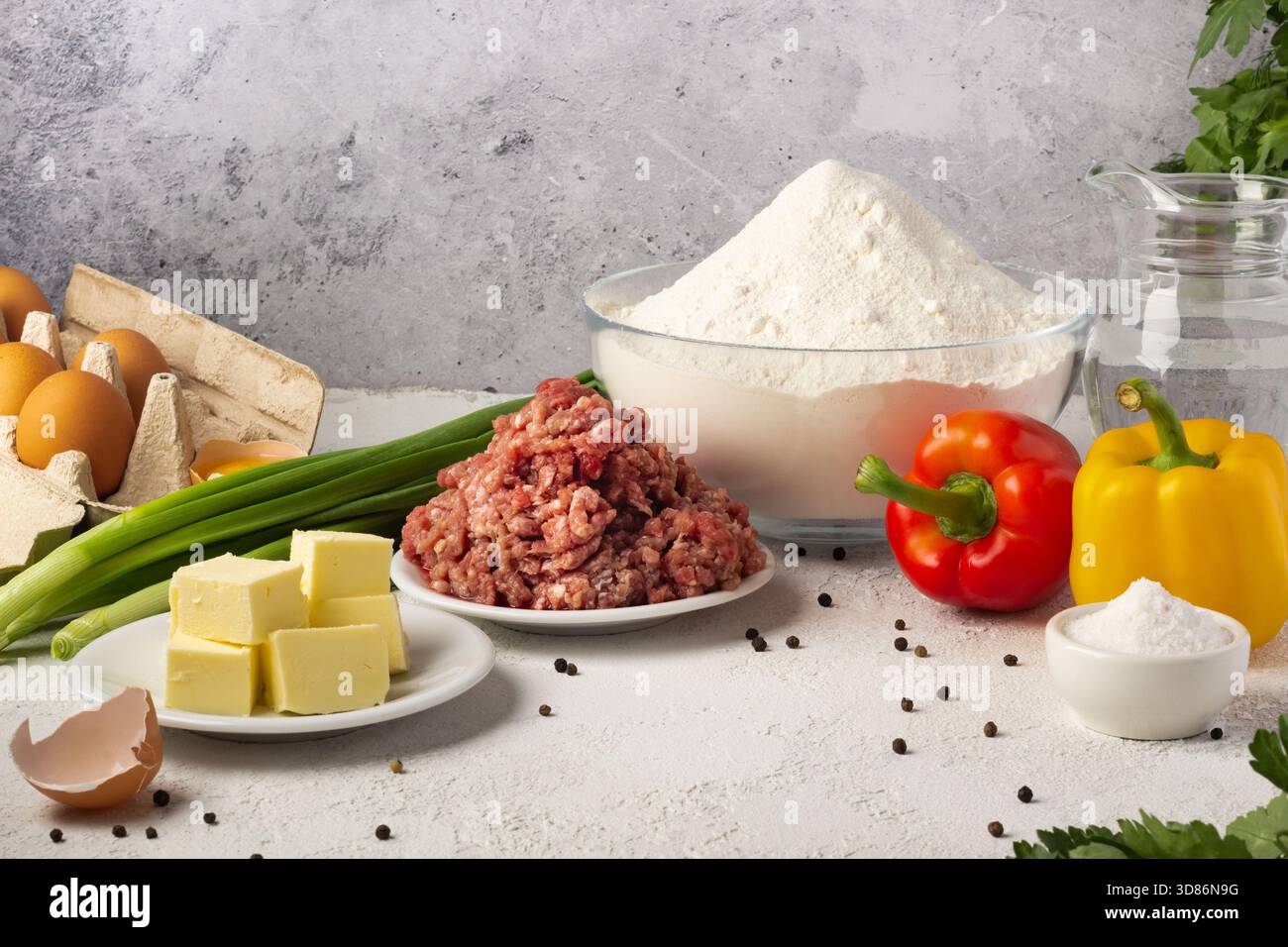 Die Zubereitung für eine köstliche Mahlzeit ist im Gange, mit frischen Zutaten, die auf einer Küchentheke ausgestellt werden, darunter Hackfleisch, buntes Gemüse, Eier, Stockfoto