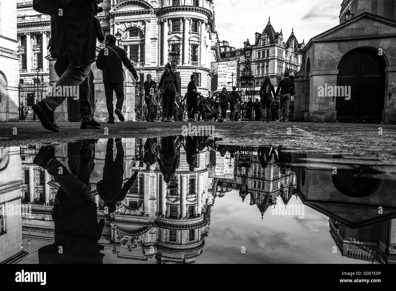 London, Großbritannien – 17. Oktober 2022 – redaktionelle Reisefotografie, die Reflexionen des Old war Office Building und der vorbeiziehenden Menschen in einer Pfütze feststellt. Stockfoto