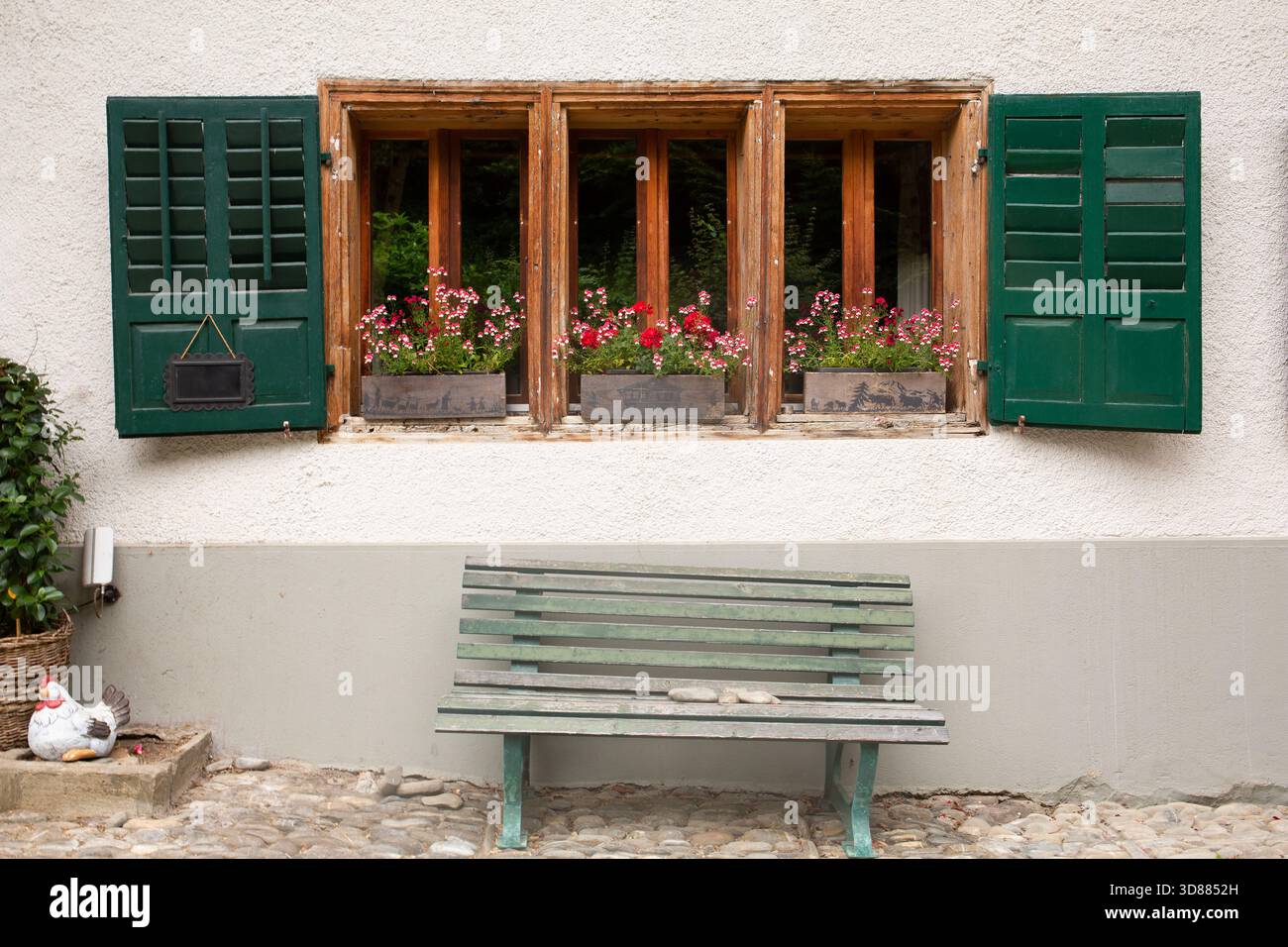 Bezaubernde Fenster mit bunten Blumen und grünen Fensterläden in Gruyeres, Schweiz Stockfoto