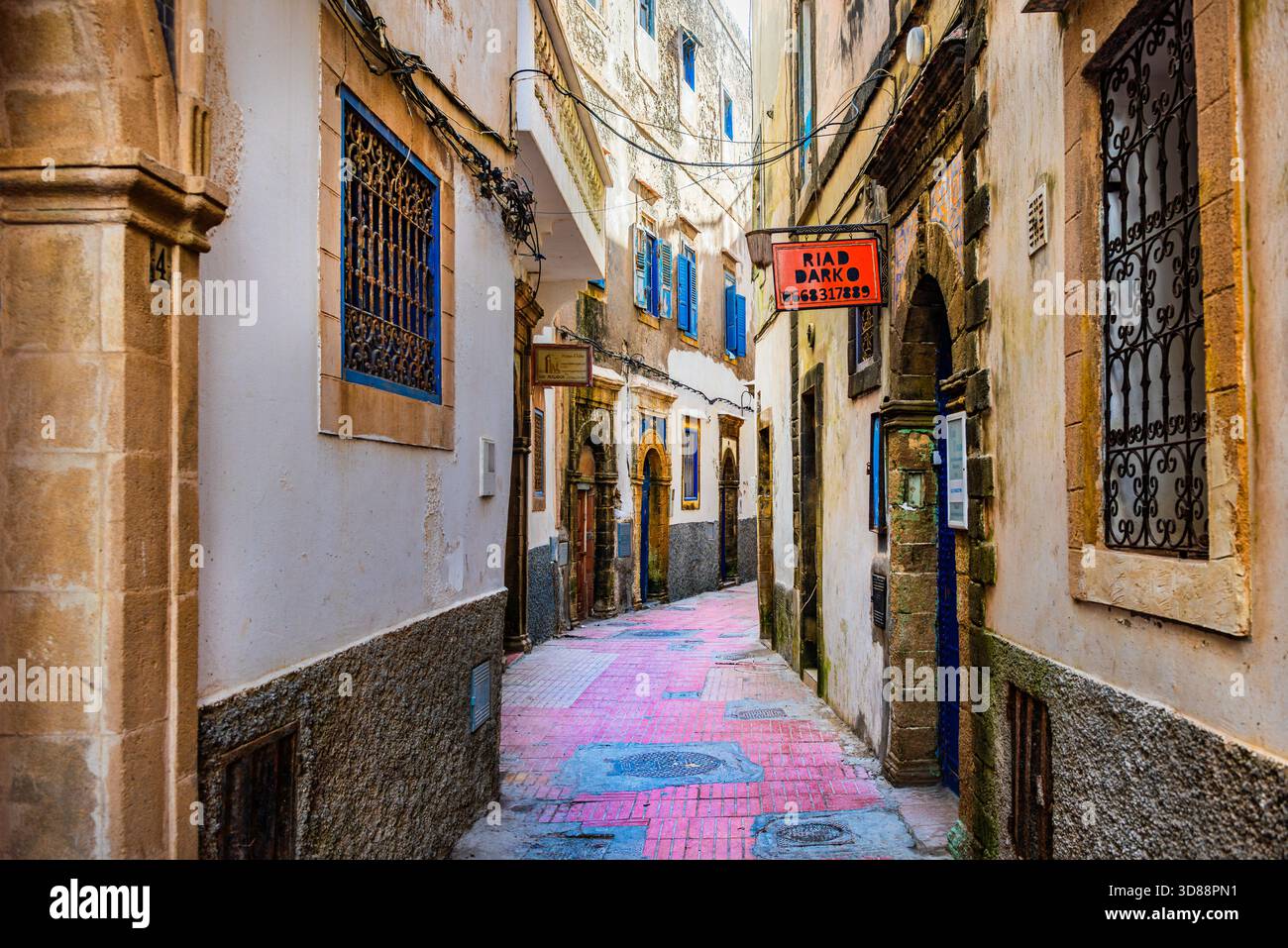 Enge Straße mit bunten Türen, blauen Fensterläden und kunstvollen Bögen in der historischen Medina Essaouira, Marokko Stockfoto