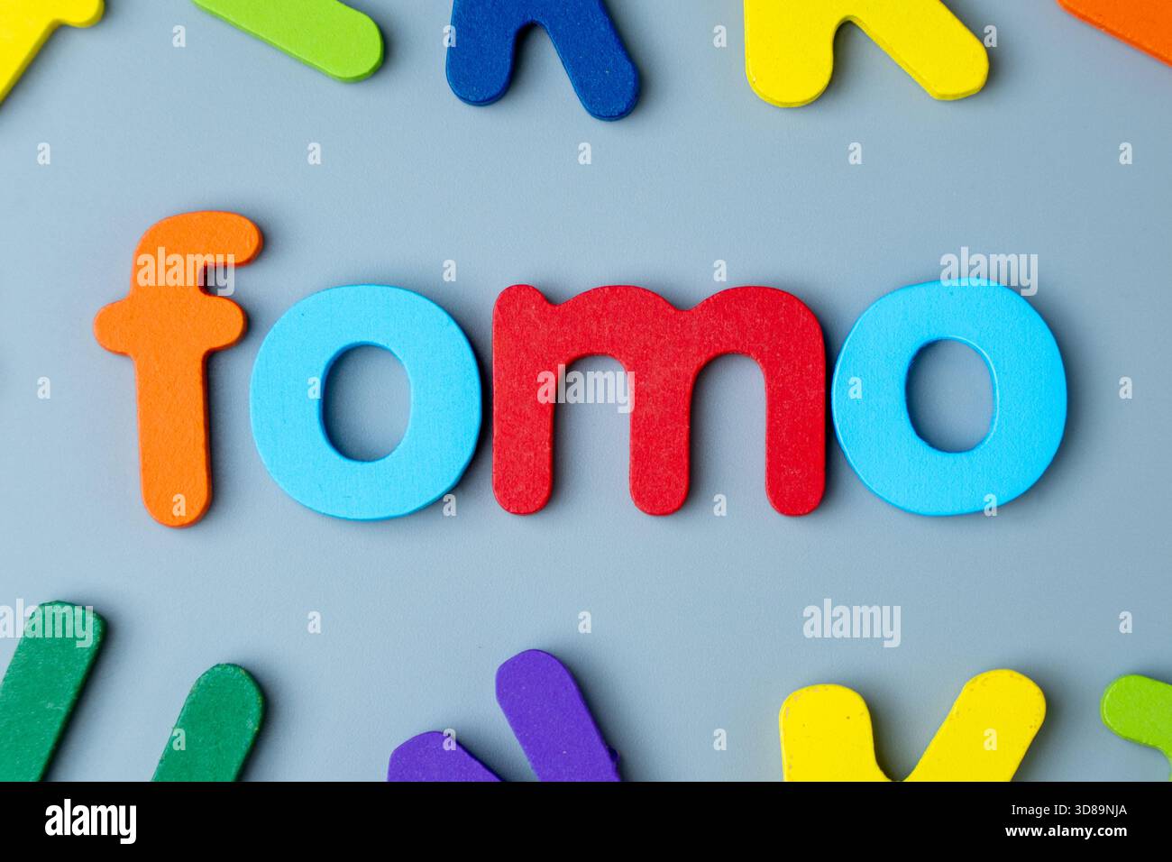 Bunte Buchstaben aus Holz, die das Wort FOMO bilden. Angst vor dem Verpassen, digitale Angst, soziales Druckkonzept. Stockfoto