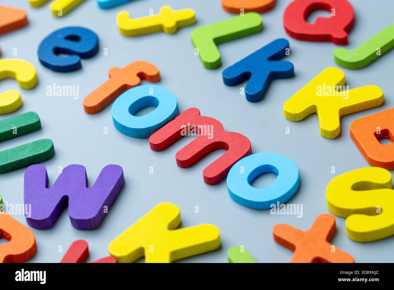 Bunte Buchstaben aus Holz, die das Wort FOMO bilden. Angst vor dem Verpassen, digitale Angst, soziales Druckkonzept. Stockfoto