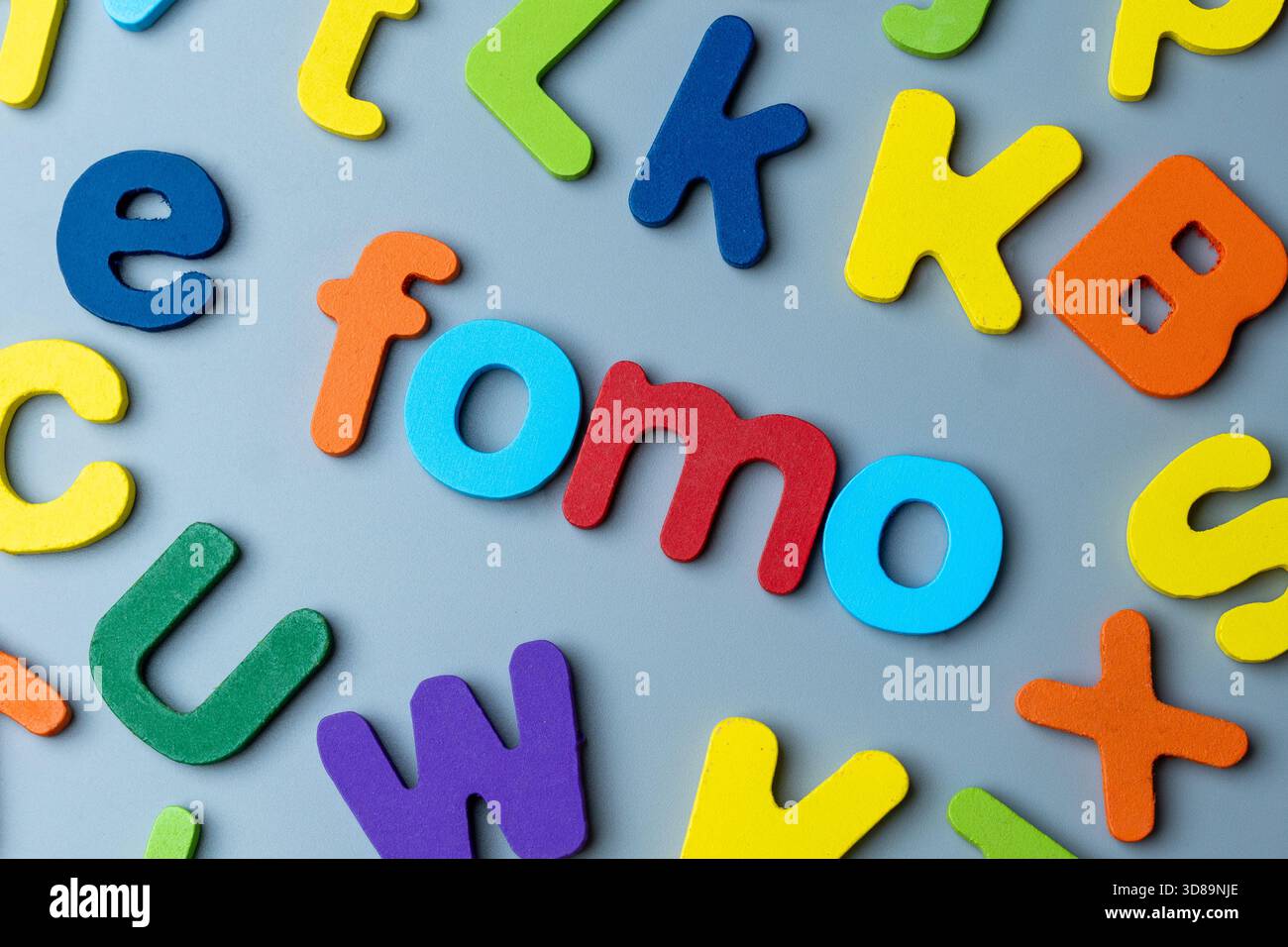 Bunte Buchstaben aus Holz, die das Wort FOMO bilden. Angst vor dem Verpassen, digitale Angst, soziales Druckkonzept. Stockfoto