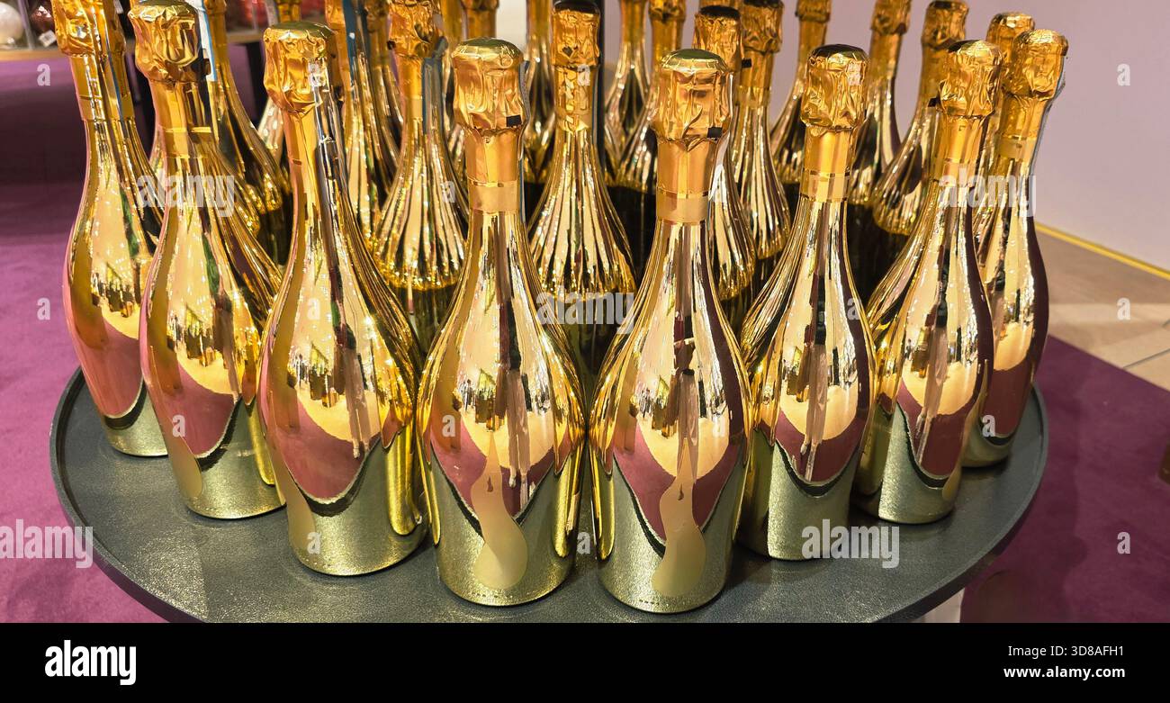 Berlin, Deutschland - 19. September 2025: Goldene Sektflaschen sind für festliche Anlässe ordentlich auf einem runden Tablett angeordnet. - Smartphone-aufgenommenes Stockfoto