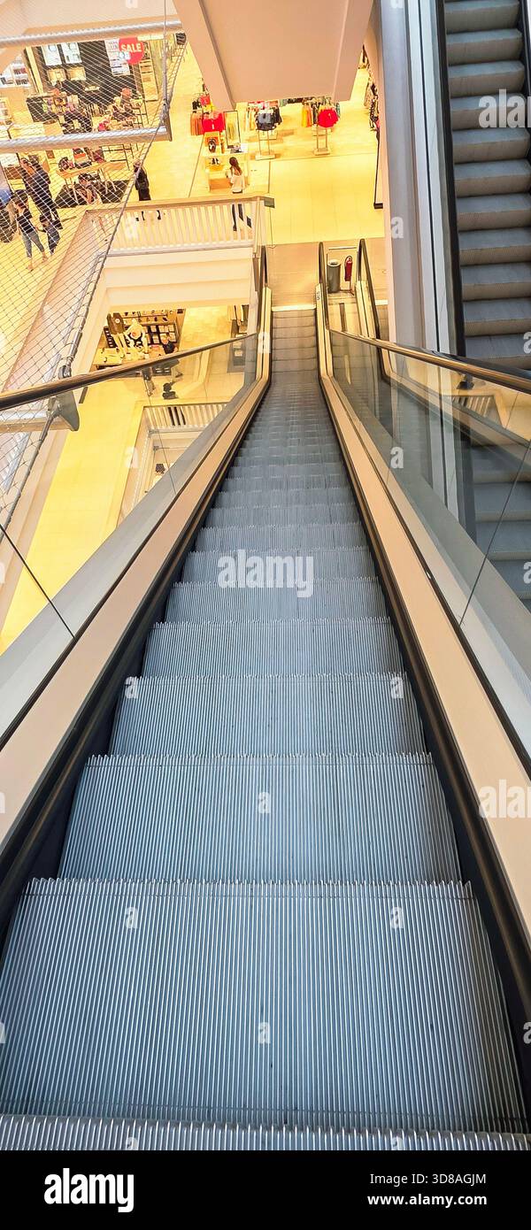 Berlin, Deutschland - 27. August 2025: . Die Rolltreppe führt hinunter in ein modernes Einkaufszentrum mit lebhafter Atmosphäre - Smartphone-aufgenommenes Stockfoto