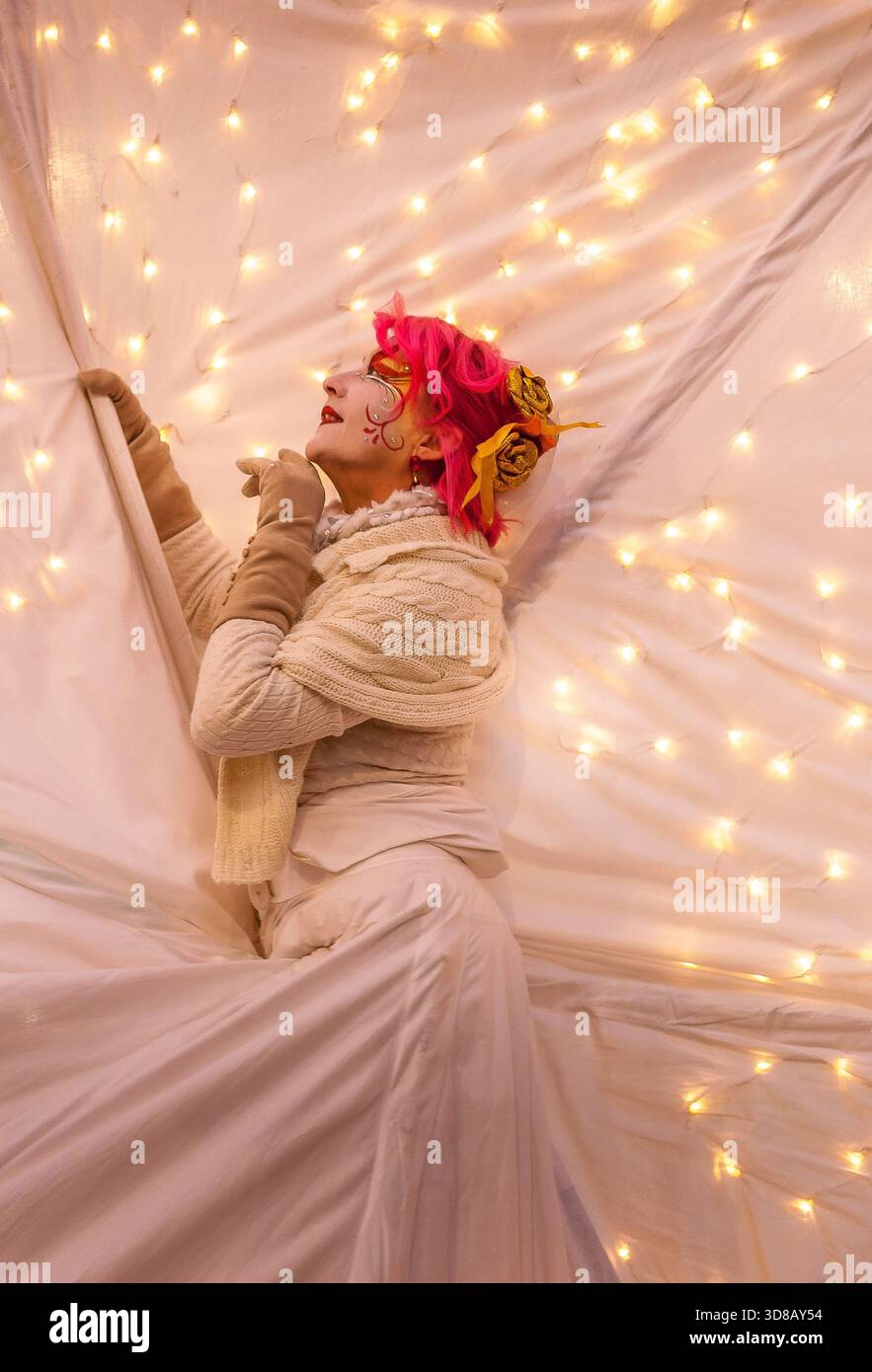Traumhafte Frau mit floralem Kopfschmuck posiert vor warmen Feenlichtern Hintergrund Stockfoto