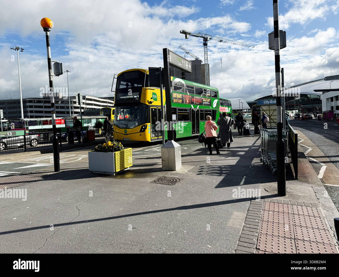 Dublin, Irland - 21. Oktober 2025: Heller Tag an einem Busbahnhof in Dublin mit einem grünen Doppeldeckerbus und Fußgängern. Stockfoto