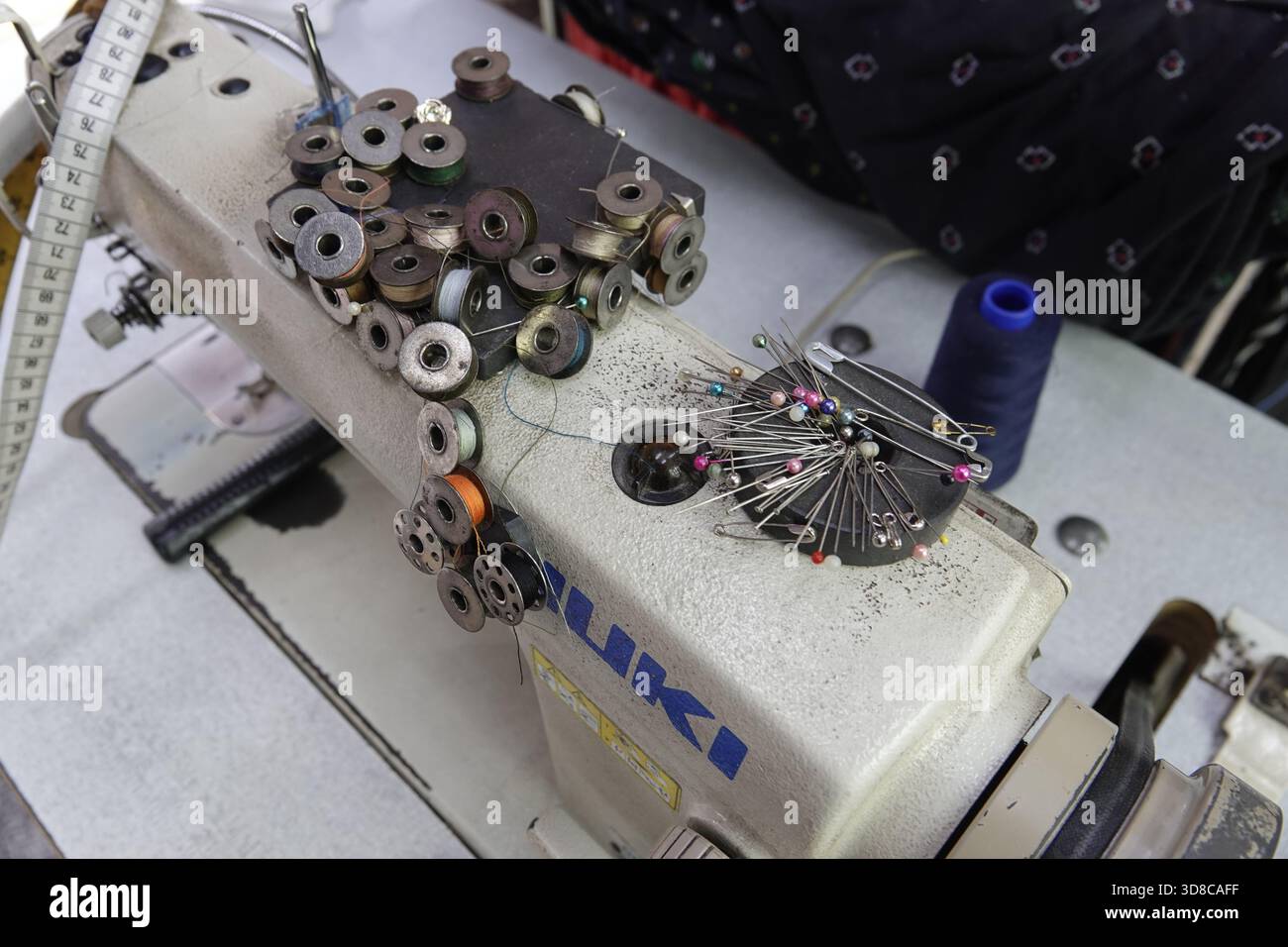 Little India, Singapur, 9. September, 2025 Thunfische und verschiedene Nadeln warten auf ihren Handwerker auf einer Nähmaschine in einem Bekleidungsrepa Stockfoto