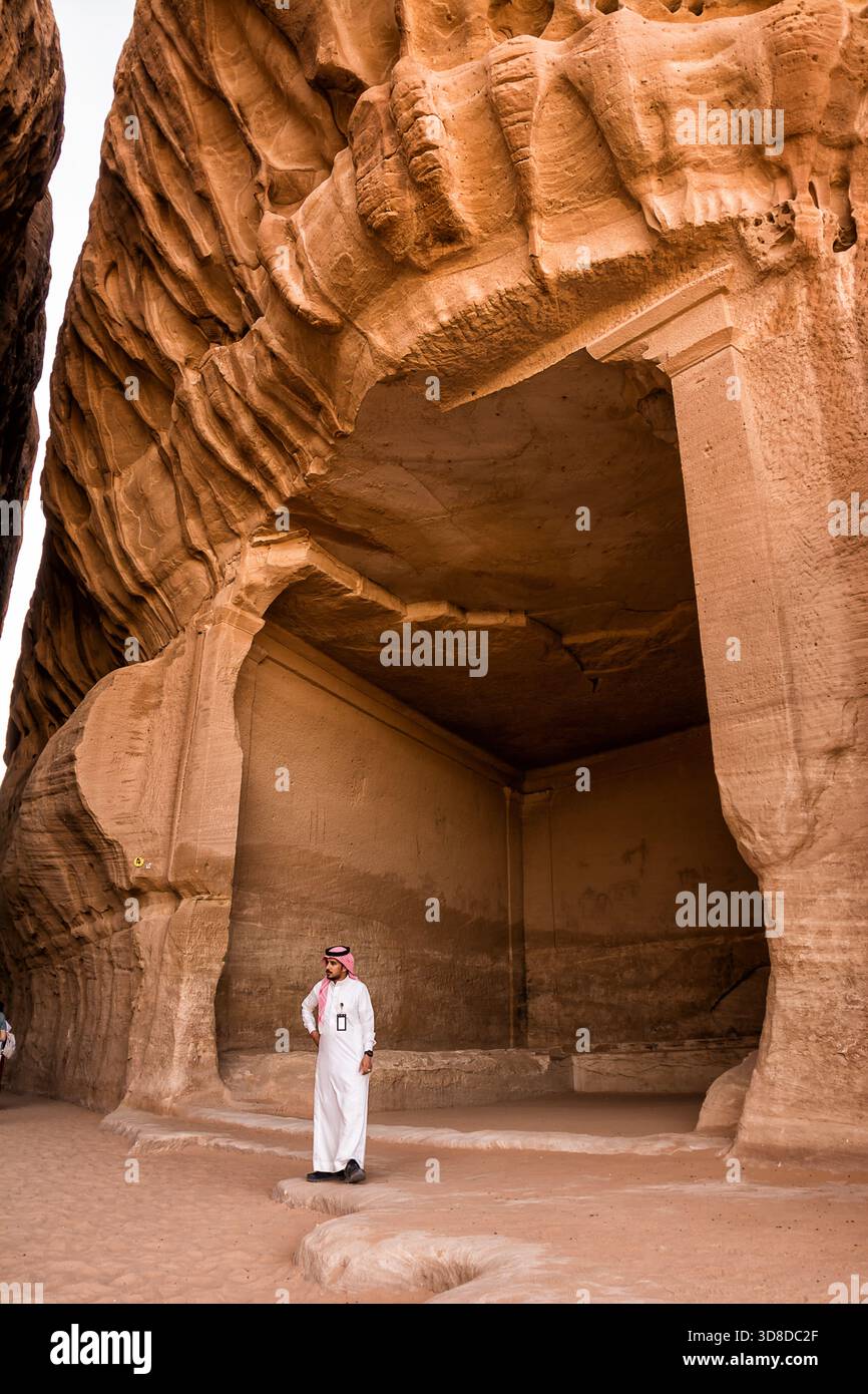 Al Ula, Saudi-Arabien - 23. April 2025: Grabkammer im Sandstein an der historischen Hegra-Stätte in Saudi-Arabien mit einem arabischen Führer in Tradition Stockfoto