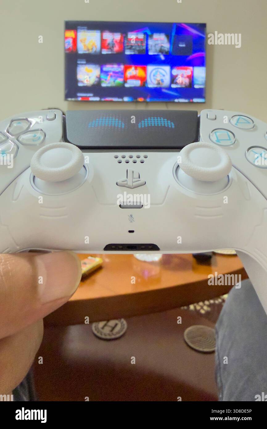 Doha, Katar - 28. November 2025: Ein Spieler spielt zu Hause Play Station 5, seine Hand hält den Dual Sense Joystick, den neuen Wireless Controller. Stockfoto