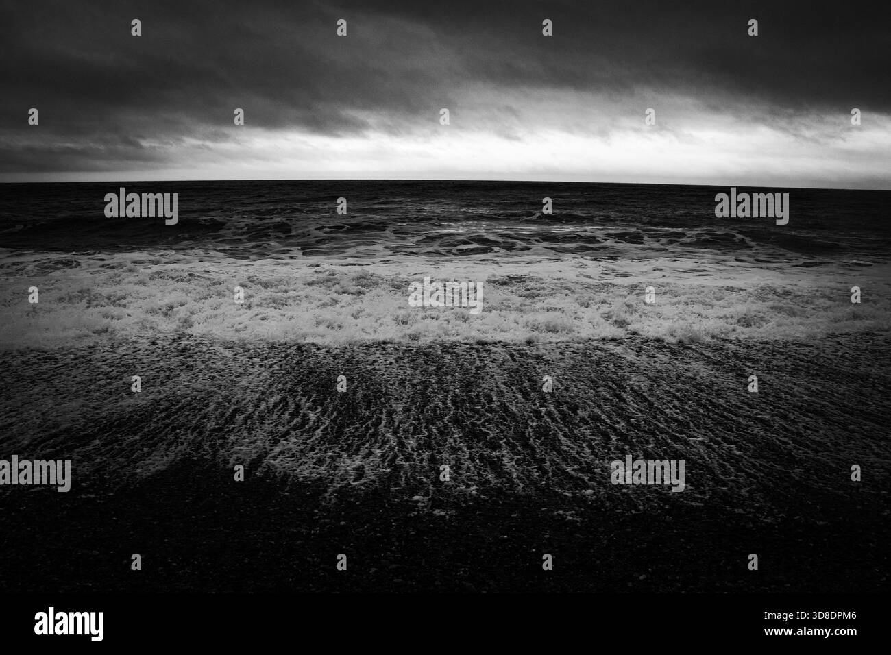 Wellen krachen am Ufer während eines Sturms mit Sturmwind über das Meer – aufgenommen in Schwarzweiß-Schwarzweiß-Schwarzweiß Stockfoto