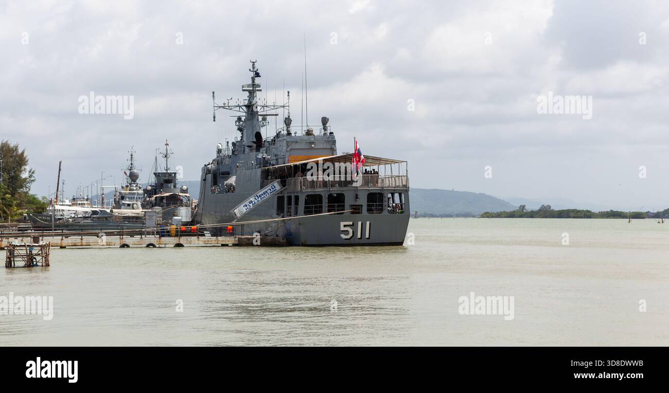Ein Militärschiff legte in einem Hafen in Songkhla, Thailand, an, mit ruhigem Wasser und einer malerischen Landschaft im Hintergrund. Stockfoto