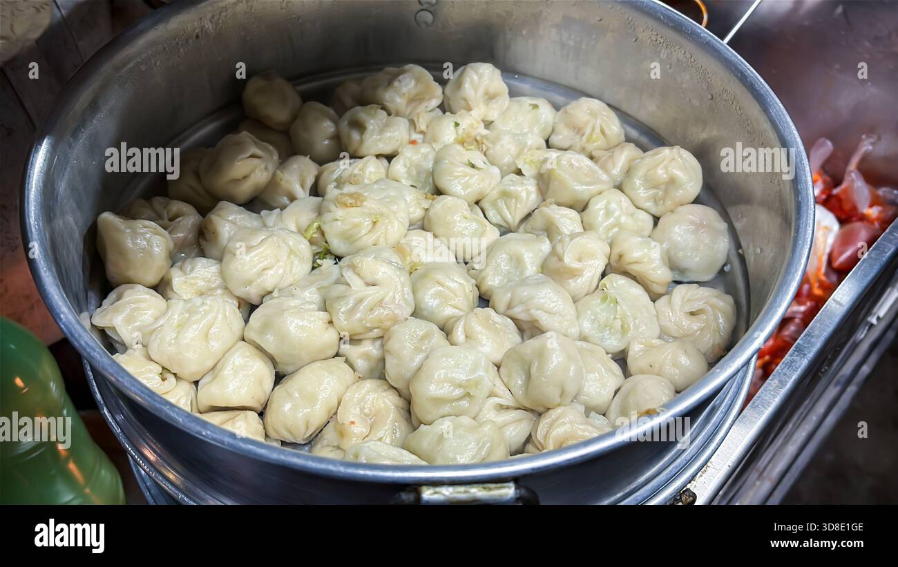 Heiße gedämpfte authentische Momos in Edelstahl-Dampfgarer im Straßenladen Stockfoto