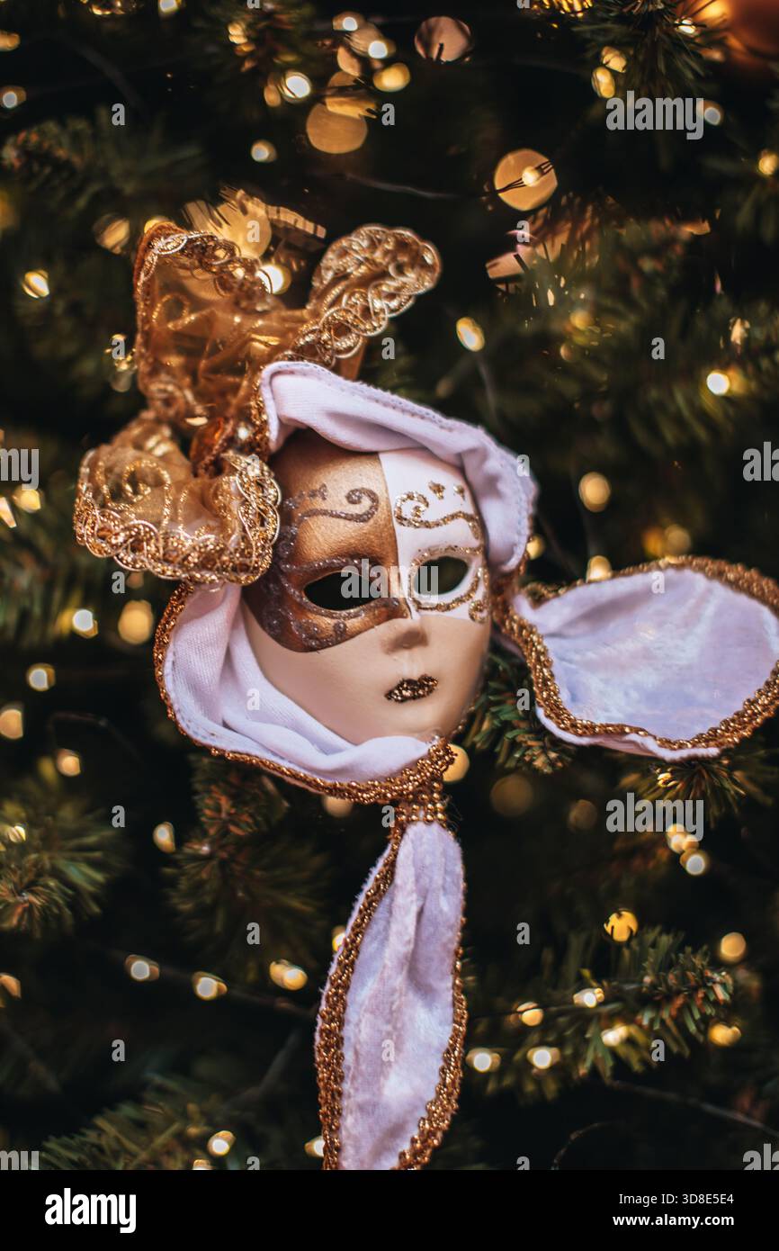 Goldene weiße Theatermaske, die an einem Weihnachtsbaum hängt, einzigartige Neujahrsdekoration, Geschenke und Souvenirs Stockfoto