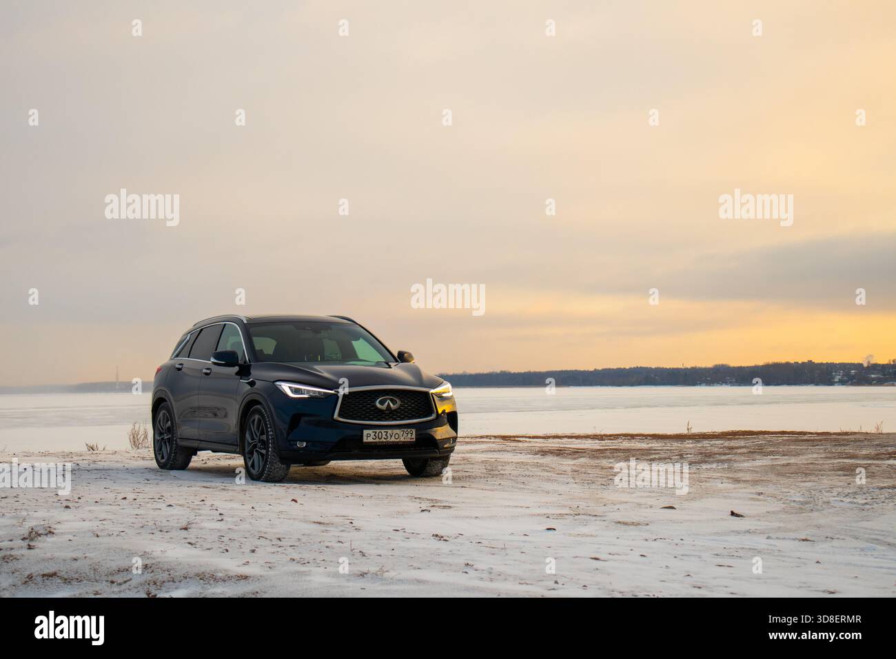 Moskau, Russland - 13. Dezember 2024: Frontansicht einer dunkelblauen Infiniti QX50-Kreuzung, die auf Schnee in der Nähe eines gefrorenen Wassers geparkt wurde Stockfoto