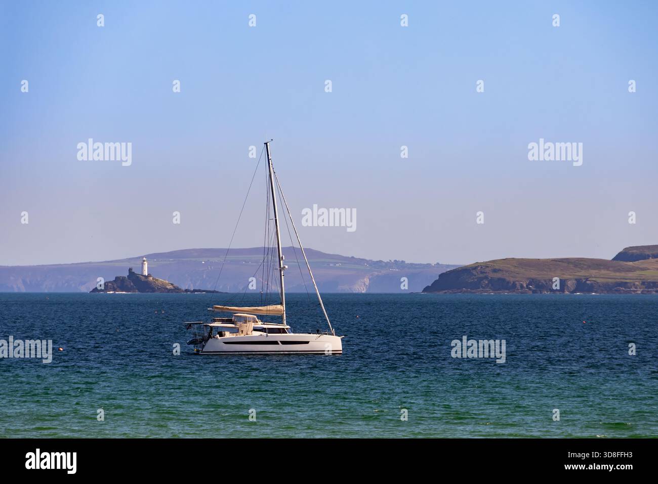 Ein Segelboot liegt in St Ives Bay, Cornwall, England, Großbritannien, Europa, mit Blick auf den Leuchtturm von Godrevy Stockfoto