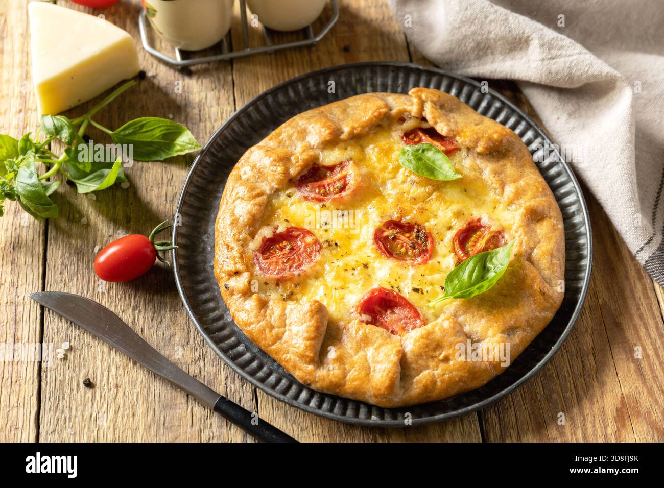 Knusprige Tomatengalette mit adyghe-Käse und Kräutern auf rustikalem Hintergrund. Stockfoto