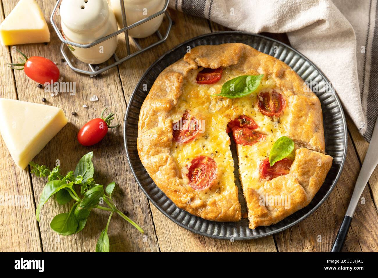 Knusprige Tomatengalette mit adyghe-Käse und Kräutern auf rustikalem Hintergrund. Stockfoto