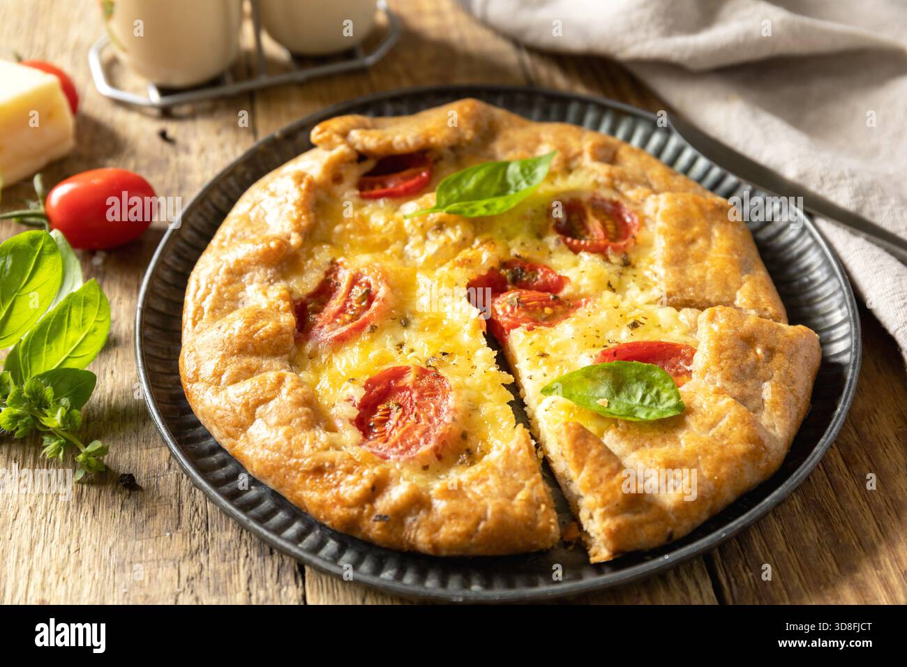 Knusprige Tomatengalette mit adyghe-Käse und Kräutern auf rustikalem Hintergrund. Stockfoto
