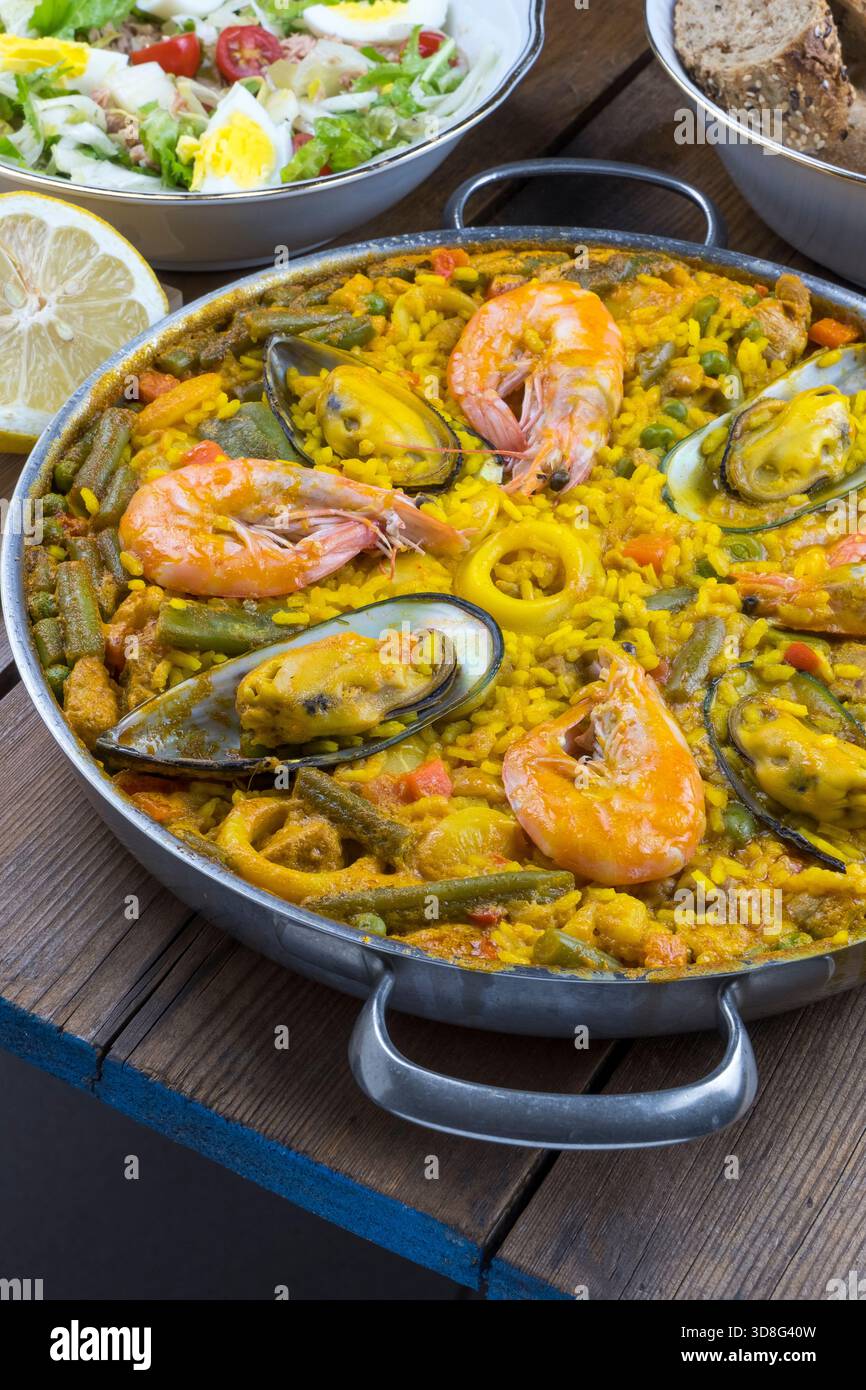 Paella und eine Schüssel Salat auf einem Tisch Stockfoto