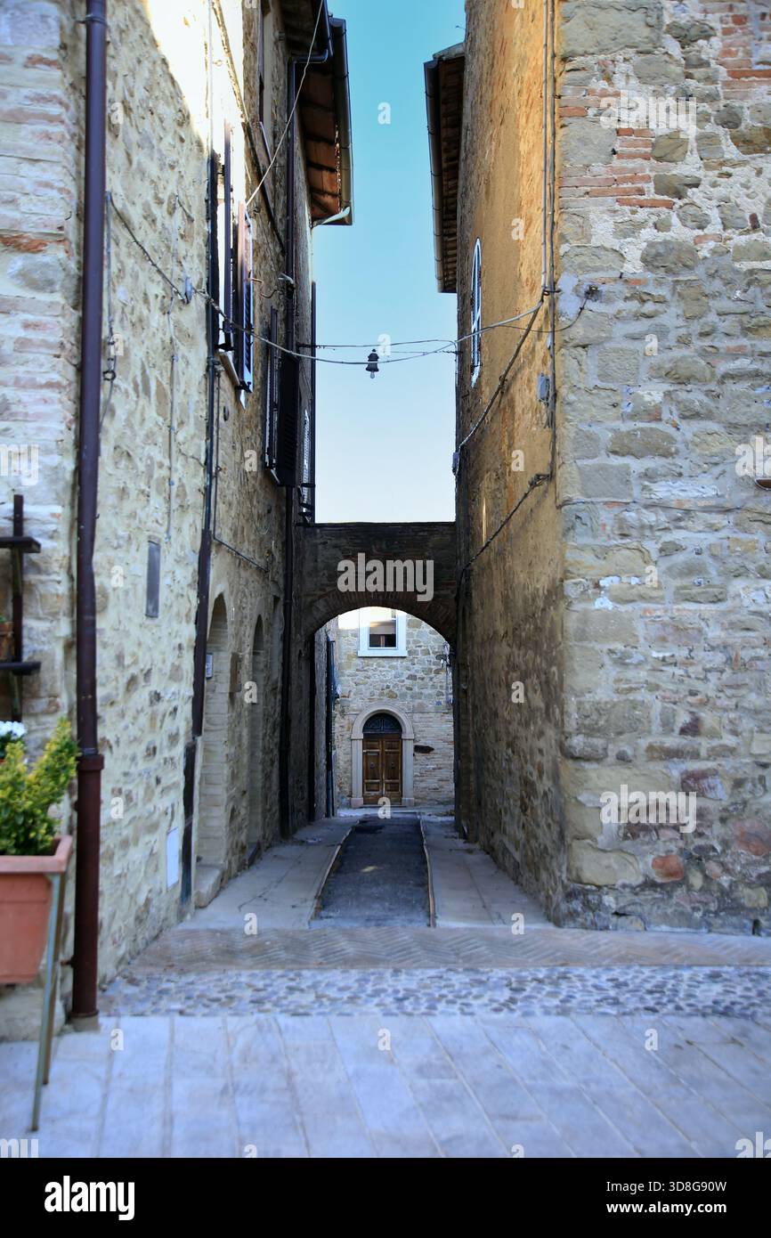 Die Perspektive einer engen Straße mit einem kleinen Bogen zwischen alten Steinhäusern, Gualdo Cattaneo, Perugia, Umbrien, Italien Stockfoto