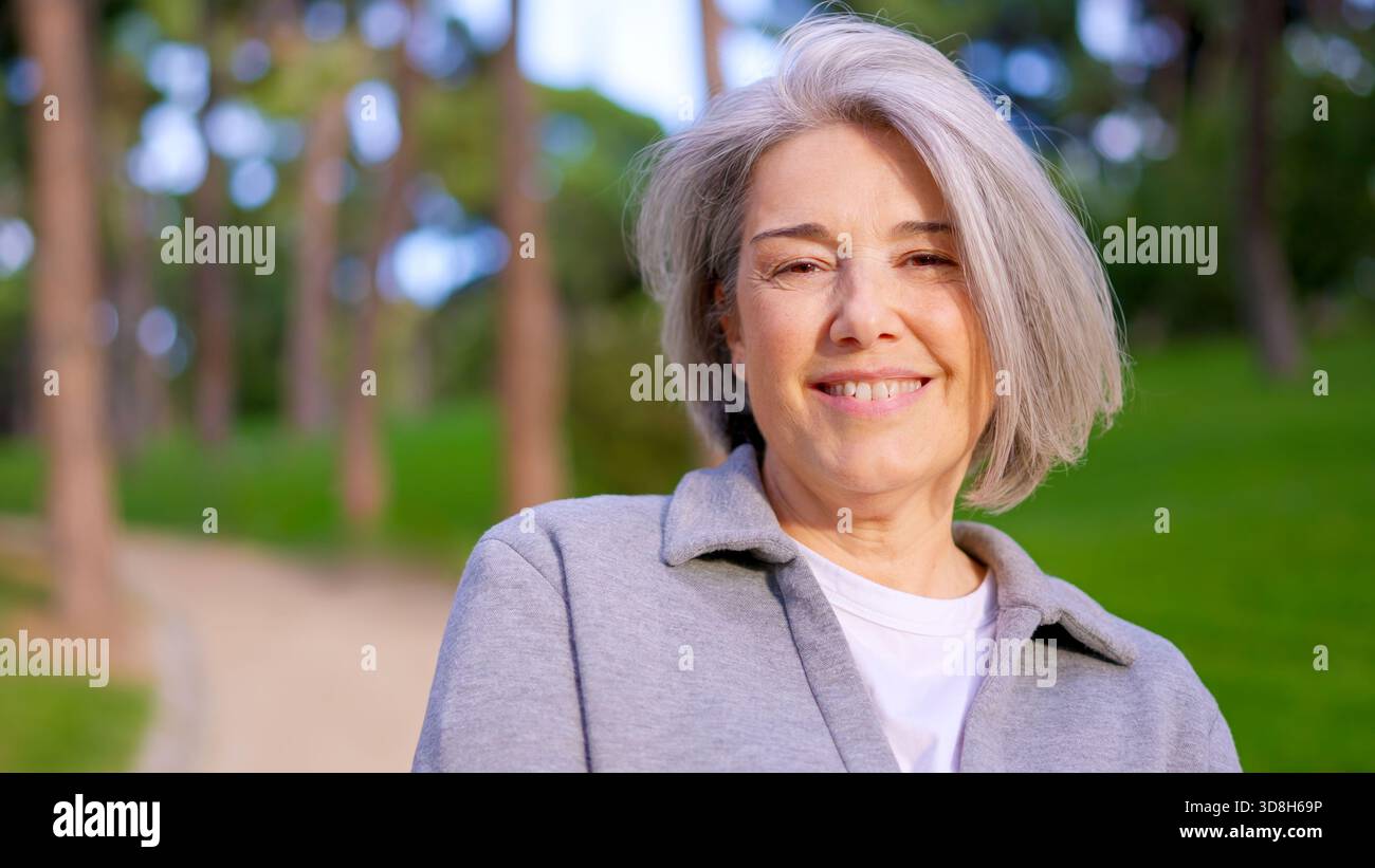 Schöne Seniorin mit grauen Haaren, die draußen lächelt Stockfoto