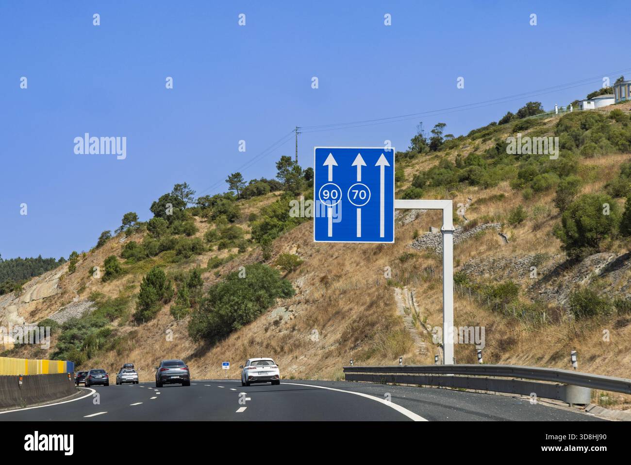 Portugiesisches Autobahnschild mit Mindestgeschwindigkeitsbeschränkungen von 90 km/h und 70 km/h für die linke und mittlere Spur. Insgesamt drei Spuren. Sonniger Tag. Stockfoto