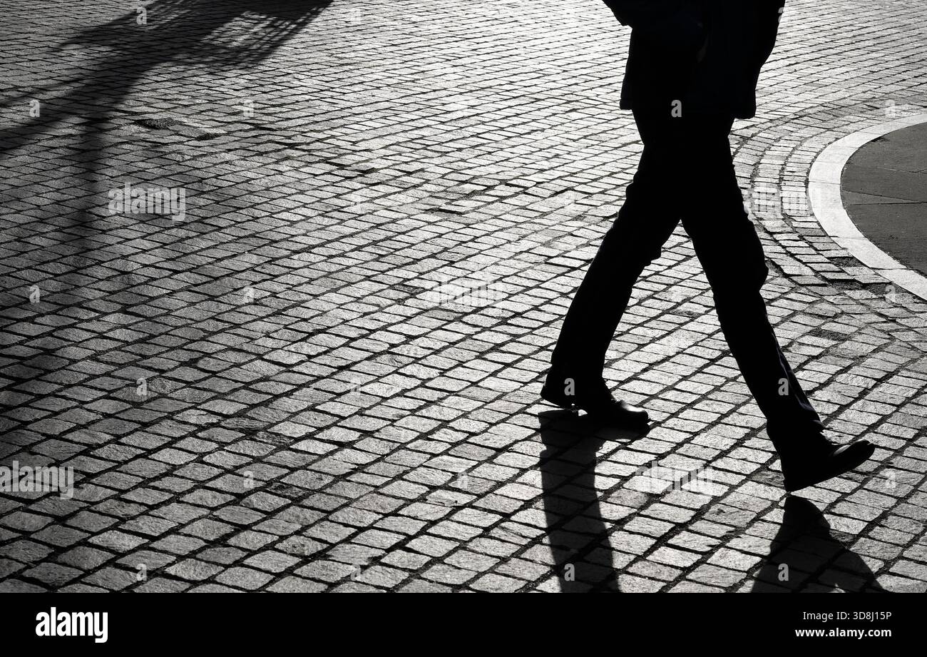 Silhouette eines Mannes, der auf einem Kopfsteinpflasterweg läuft, norfolk, england Stockfoto