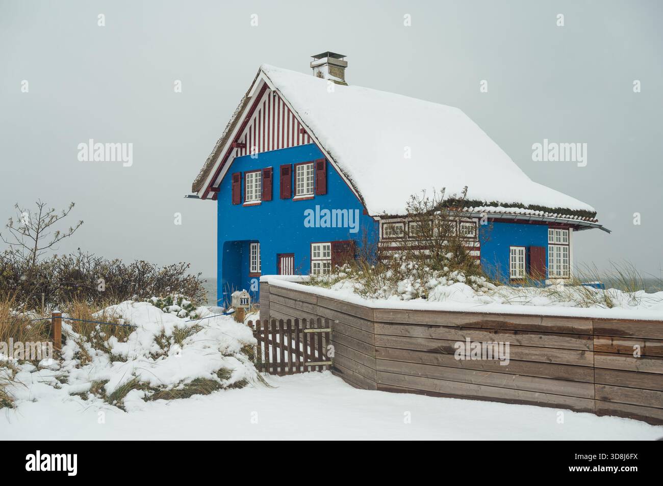 Blaues Reetdachhaus mit Schnee bedeckt, Graswarder, Heiligenhafen Stockfoto