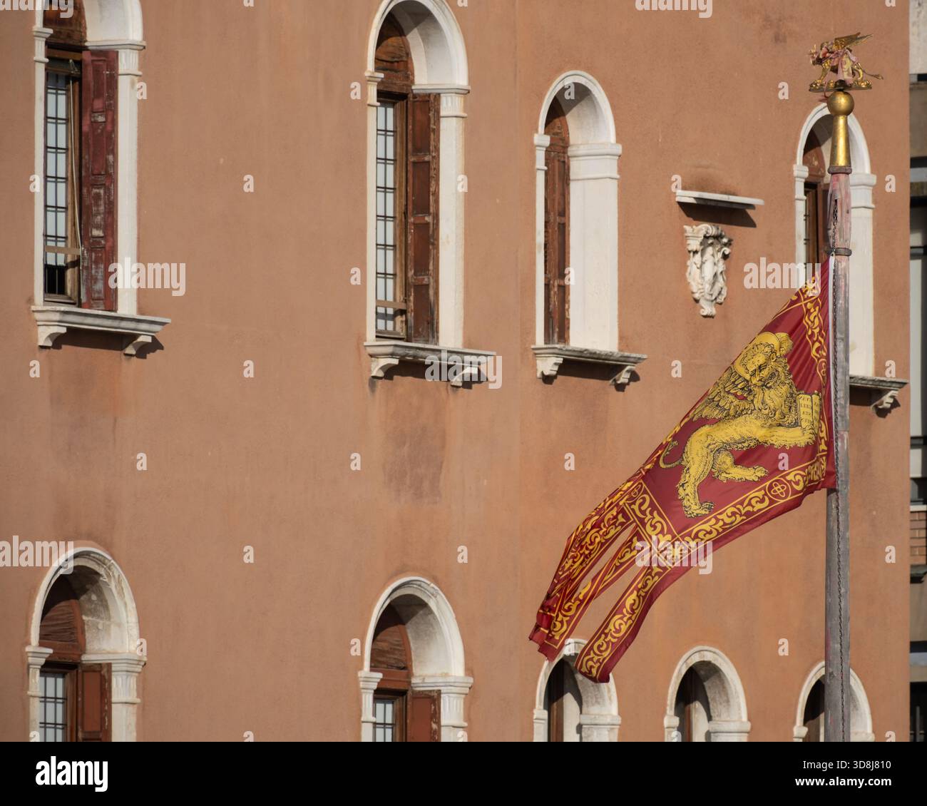 Flagge der Region Veneto mit dem geflügelten Markuslöwen, der vor historischen Gebäudefassaden in Venedig, Italien, fliegt. Stockfoto
