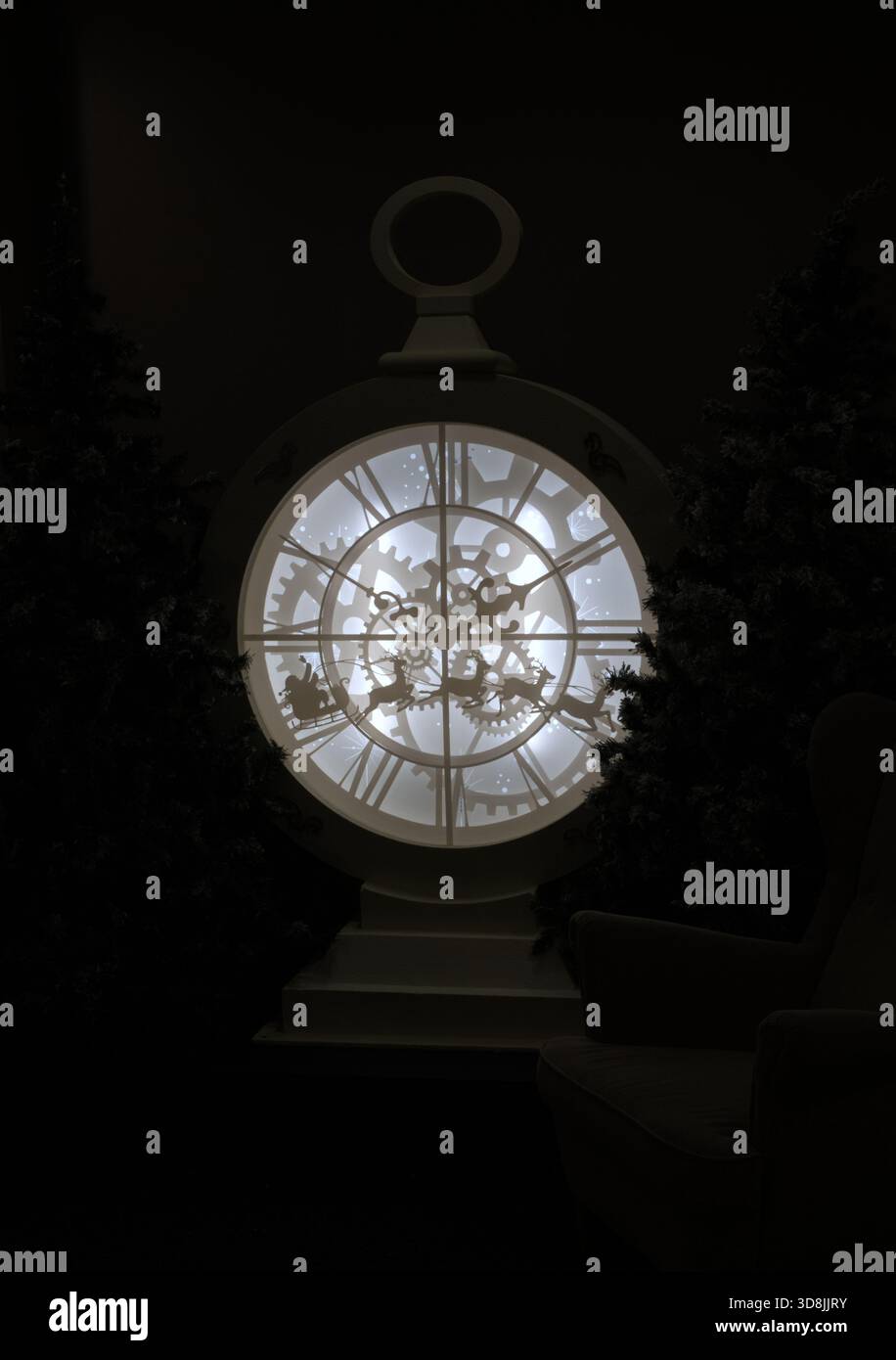 Eine Taschenuhr im Steampunk-Stil mit römischen Ziffern und festlichen Silhouetten des Pferdes des Weihnachtsmanns, flankiert von Weihnachtsbäumen Stockfoto