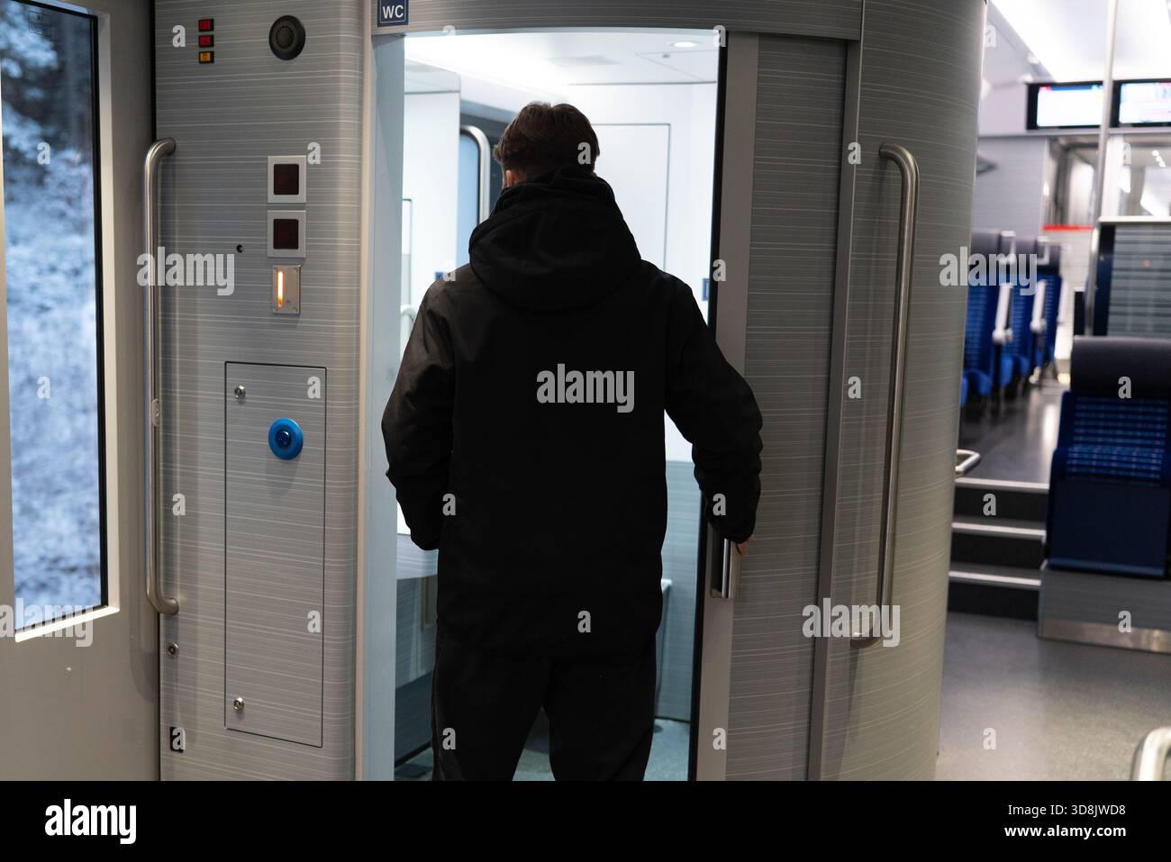 Der Passagier öffnet während der Fahrt die Tür der Zugtoilette Stockfoto