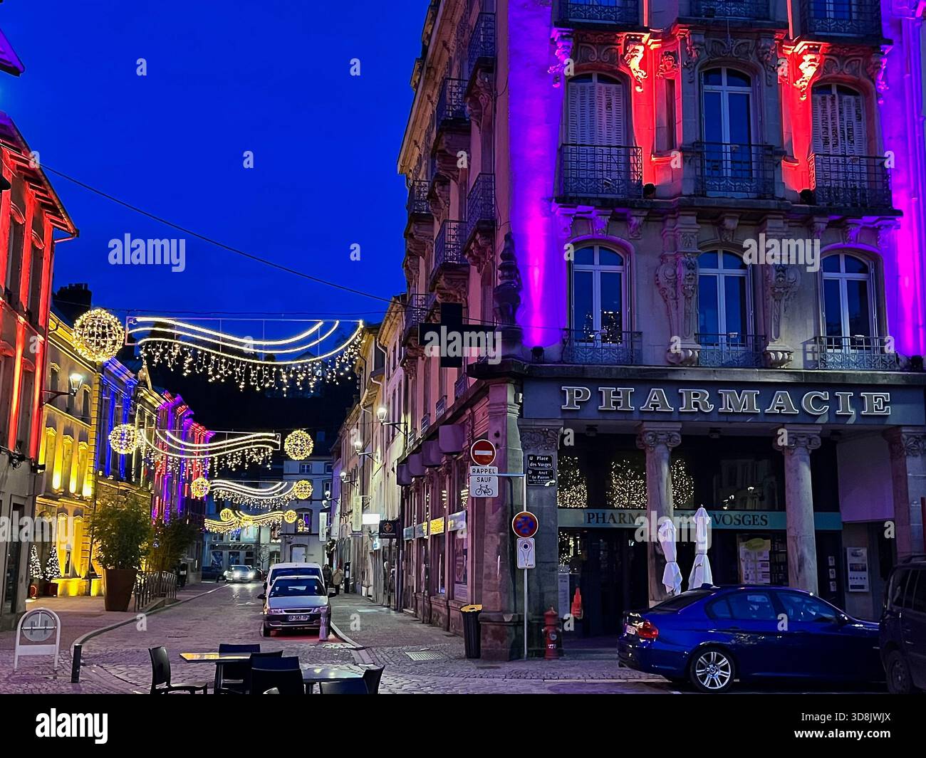 Epinal, Frankreich – 21. Dezember 2024: Beleuchtete Straße mit bunten Gebäudefassaden und festlichen Lichtinstallationen, lebhafte Abendatmosphäre - Smartphone-aufgenommenes Stockfoto