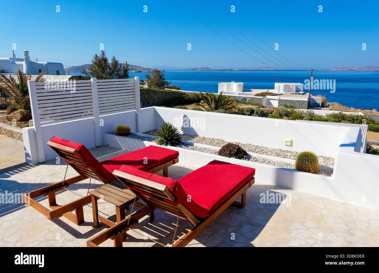 Mykonos, Kykladen, Griechenland - Themenfoto: Urlaub in Griechenland, Liegestühle auf der Terrasse eines Boutique-Hotels mit Meerblick. Stockfoto