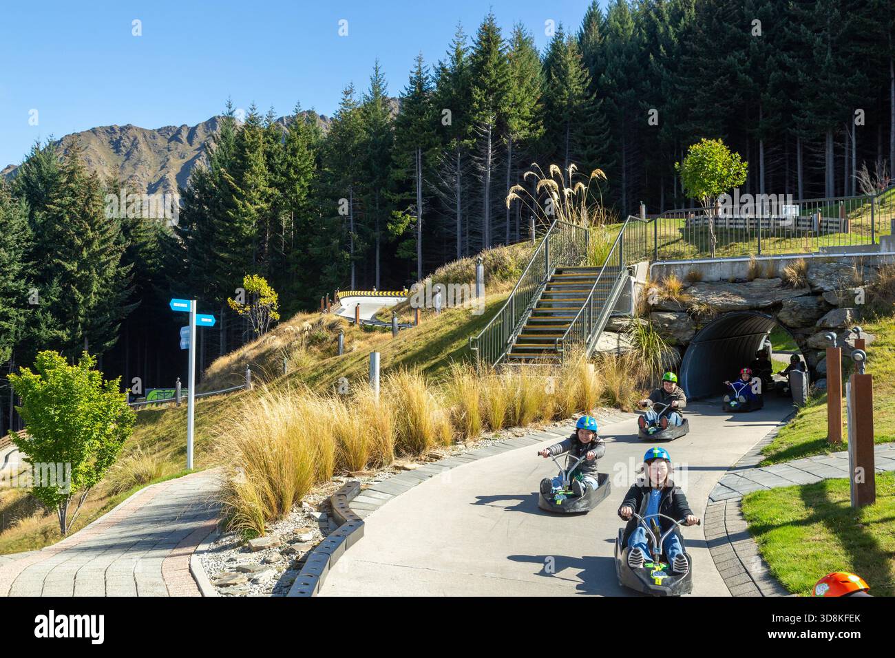 Menschen, die eine aufregende Fahrt mit dem Skyline-Rennrodel in Queenstown, Otago, Neuseeland, genießen Stockfoto