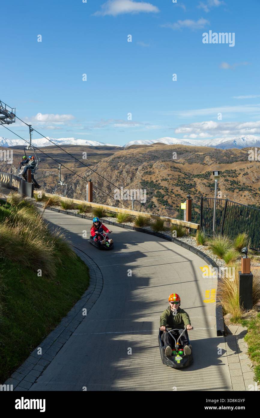 Menschen, die eine aufregende Fahrt mit dem Skyline-Rennrodel in Queenstown, Otago, Neuseeland, genießen Stockfoto