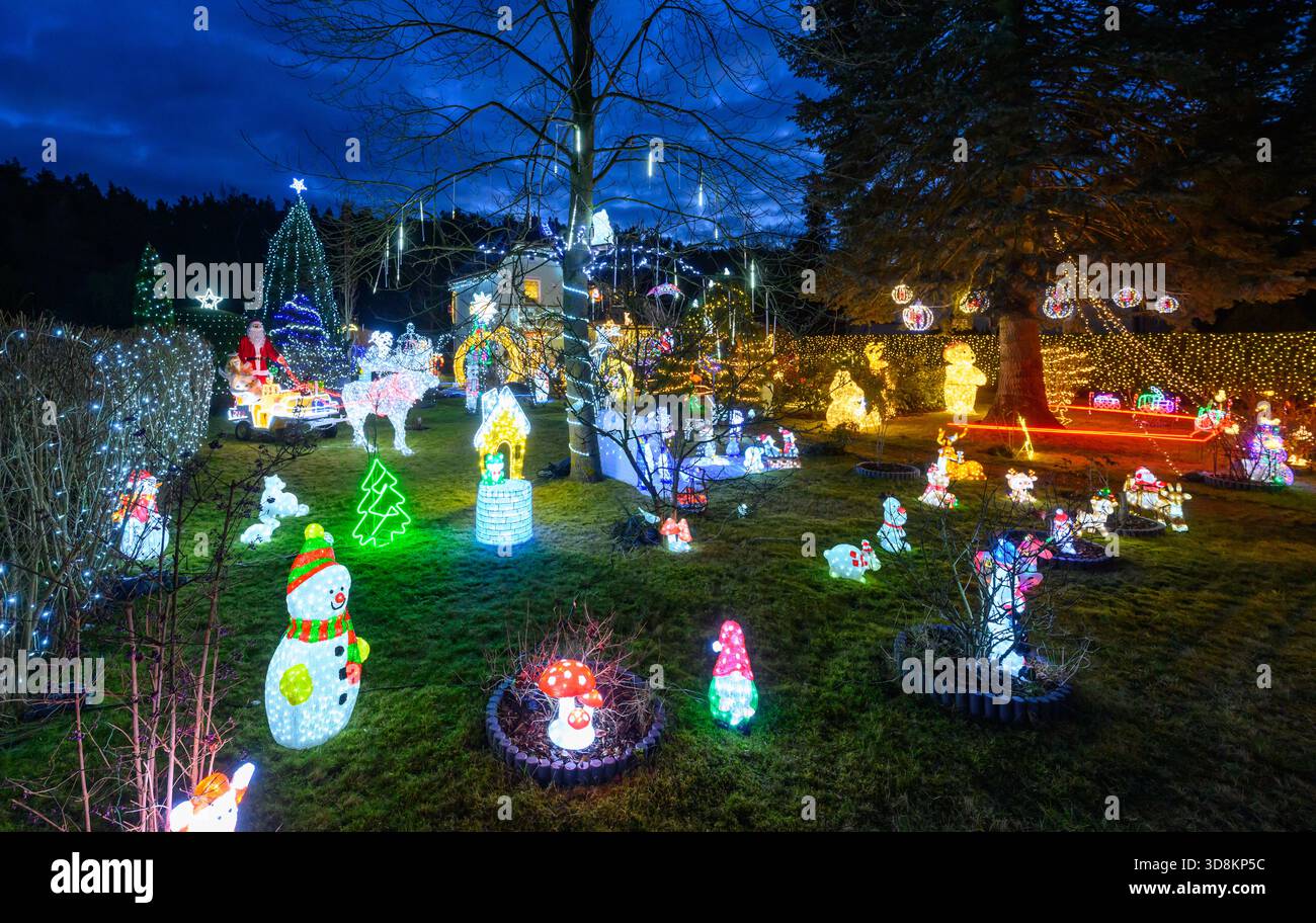 01. Dezember 2025, Brandenburg, Berkenbrück: Jeden Abend verwandelt sich das Anwesen der Familie Muschner in Ostbrandenburgs in ein glitzerndes Winterwunderland. Mehr als 20 Zeitgeber beleuchten die Garten- und Hausfassade im Takt und tauchen das Anwesen in ein Lichtmeer. Die Sammlung wächst seit über zwei Jahrzehnten stetig: Mehr als 100 Figuren bevölkern das Gelände – glitzernde Schneemänner, strahlende Weihnachtsmänner, Rentiere und andere Tierfiguren. Zusammen bilden sie ein leuchtendes Ensemble, das die Besucher aus der Ferne in festliche Stimmung versetzt und den Garten zu einem beliebten Ausflugsziel während der Adv. Macht Stockfoto