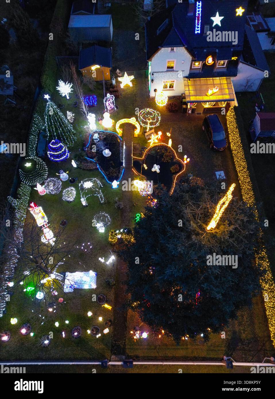 01. Dezember 2025, Brandenburg, Berkenbrück: Jeden Abend verwandelt sich das Anwesen der Familie Muschner in Ostbrandenburgs in ein glitzerndes Winterwunderland (Luftaufnahme mit Drohne). Mehr als 20 Zeitgeber beleuchten die Garten- und Hausfassade im Takt und tauchen das Anwesen in ein Lichtmeer. Die Sammlung wächst seit über zwei Jahrzehnten stetig: Mehr als 100 Figuren bevölkern das Gelände – glitzernde Schneemänner, strahlende Weihnachtsmänner, Rentiere und andere Tierfiguren. Zusammen bilden sie ein leuchtendes Ensemble, das die Besucher von weitem in festliche Stimmung versetzt und den Garten zu einem beliebten Ort macht Stockfoto