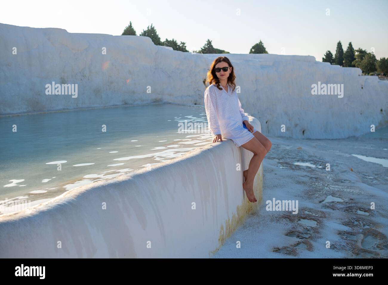 Ein Besucher genießt die einzigartige Schönheit von Pamukkale, die sich auf einem Travertinvorsprung neben den warmen Thermalbecken unter klarem Himmel ausruhen. Stockfoto