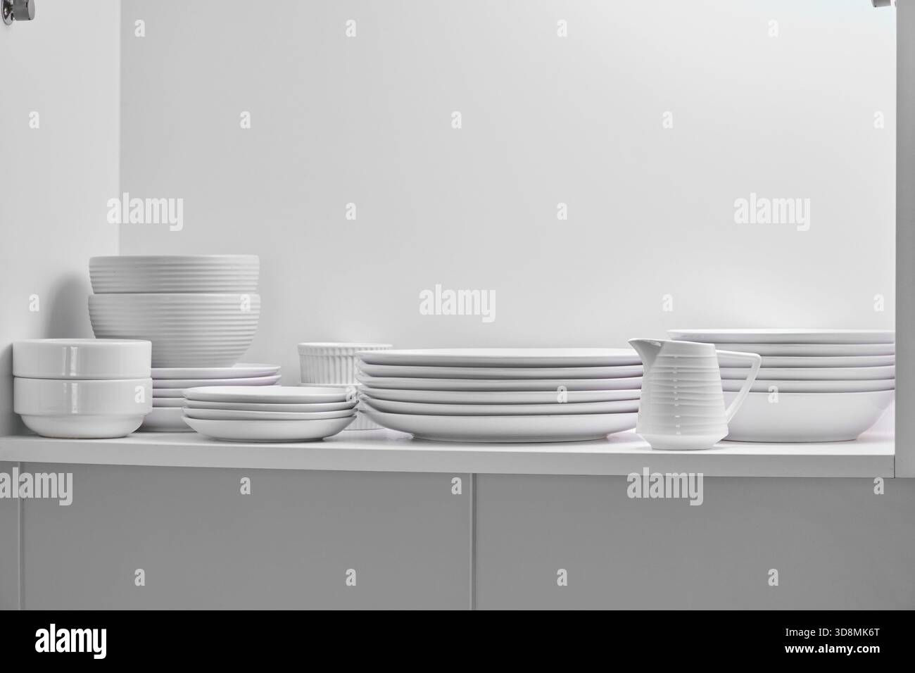 Die weißen Keramikschalen sind ordentlich angeordnet und bieten praktischen Stauraum für den Haushalt und eine minimalistische Küchenorganisation Stockfoto