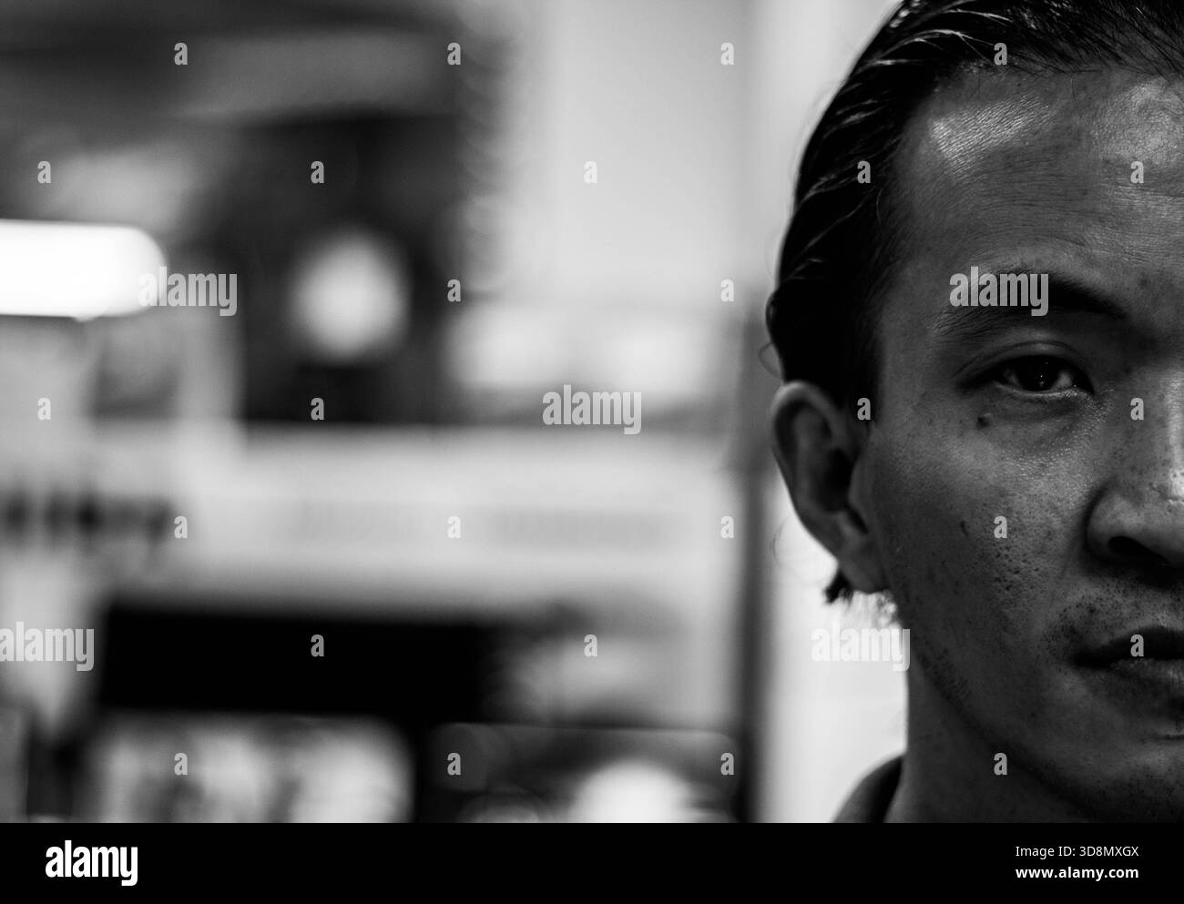 Ein besinnlicher junger Mann blickt direkt in die Kamera in einem krassen Schwarz-weiß-Porträt. Stockfoto