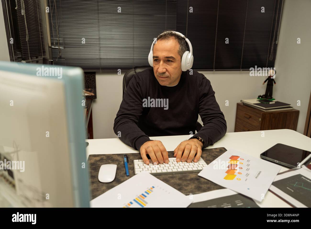Mann, der sich auf Geschäftsdaten konzentriert und auf eine Computertastatur tippt Stockfoto
